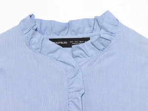 Macro shot of blue striped poplin shirt neckline with ruffled stand collar and brand label