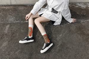 Detailed view of mid-calf cotton socks with artistic face patterns on model legs