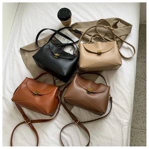 Flat lay of multiple leather handbags in black, beige, and brown with gold buckles