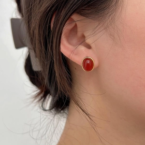Close-up of 925 sterling silver oval red agate stud earrings on female ear with gold plating