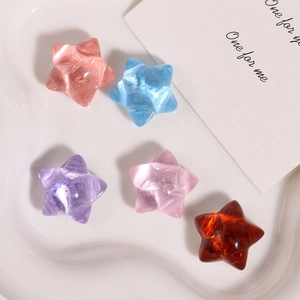 Macro shot of 5 pearlescent resin star charms in pastel colors on a white tray