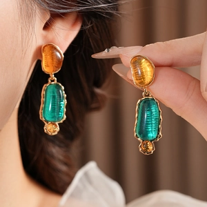 Detail view of vintage resin oval earrings in yellow and green with gold metal trim on model