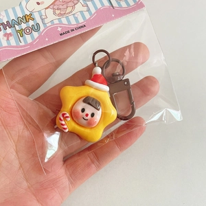 Détail d'un porte-clés de Noël en étoile jaune avec chapeau rouge et sucre d'orge