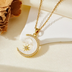 Gros plan du pendentif lune et étoile doré avec nacre blanche sur tissu en soie