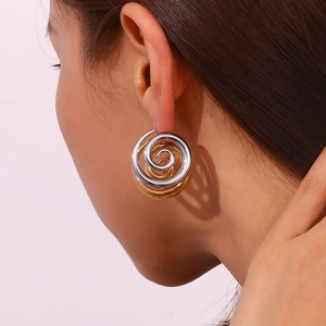 Detail of model wearing gold and silver spiral twist earrings with a metallic finish