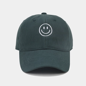 Detailed view of white smile face embroidery on dark green cotton baseball cap texture