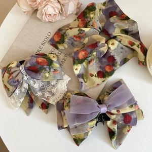 Detail of floral chiffon bow hair clip with lace, pearls and vintage oil painting patterns