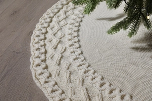 Close-up of beige knitted Christmas tree skirt featuring diamond and chain stitch patterns