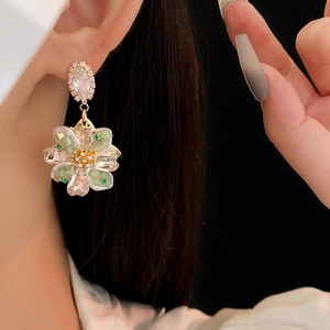 Gros plan de boucles d'oreilles fleurs en cristal avec pétales verts et champagne