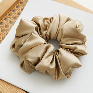 Detailed view of large champagne silk satin scrunchie with soft padded pleats texture