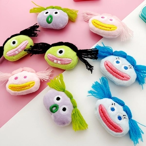Detail of colorful plush cartoon monster accessories with embroidery and braided hair