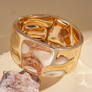 Detail showing the hammered texture and golden metallic finish of the wide cuff bracelet