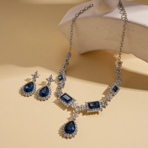 Set gioielli vintage con cristalli blu a goccia e perni d'argento su sfondo pietra