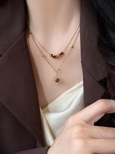 Close-up of double-layered gold tiger eye sunflower necklace on model in brown blazer