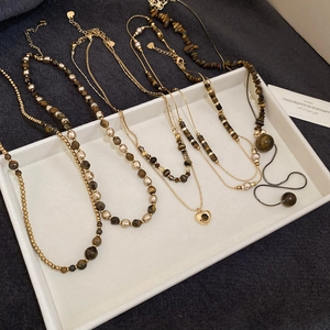 Detailed flat lay of tiger eye bead necklaces with gold heart pendants on a white tray