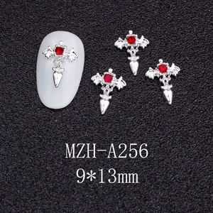 Macro shot of silver gothic bat wing cross nail charm with a red rhinestone inlay