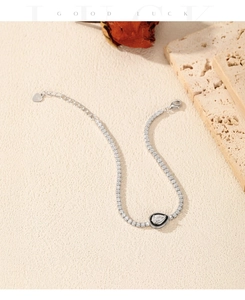 Macro detail of S925 sterling silver tennis bracelet with black enamel teardrop charm