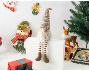 Detailed view of Christmas gnome with brown striped legs and knit hat in festive setting