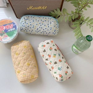 Detailed view of three quilted floral and checkered cosmetic pouches in a cozy setting