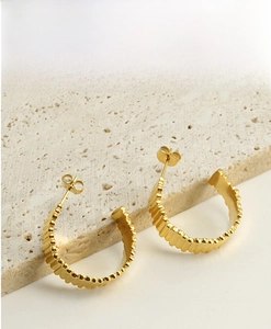 Detail of 18K gold plated C-shaped geometric earrings with a vertical grooved texture