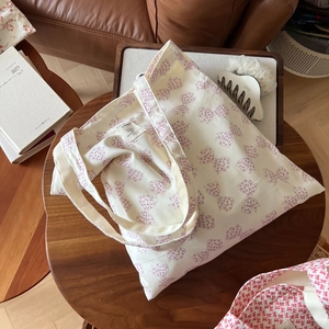 Détail du sac cabas en toile avec motifs nœuds roses et étiquette tissée de marque