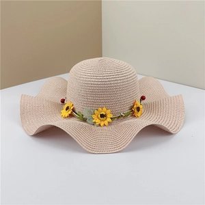Detail of beige straw hat featuring sunflower decor and a wavy brim for sun protection