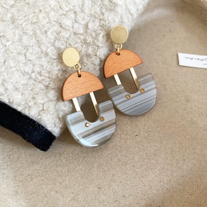 Detail view of geometric U-shaped drop earrings with wood resin and gold metal accents