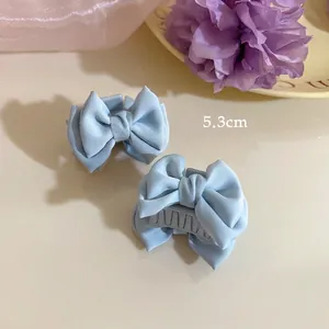 Detail view of a 5.3cm light blue satin bow hair claw clip with plastic teeth for women