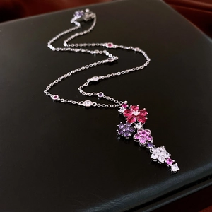 Macro detail of silver floral necklace with pink and purple zircon stones on black leather