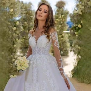 Luxurious white lace bridal gown with deep V-neck and long sleeves in a garden setting