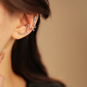 Macro detail of a silver snake-shaped ear cuff with sparkling zircons worn on ear