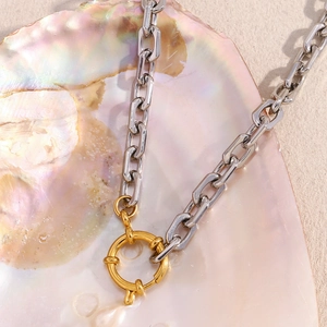 Minimalist silver and 18K gold-plated stainless steel square link chain necklace on a shell