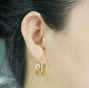 Close-up of model wearing 18K gold plated double hoop earrings with textured finish