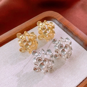 Detail of floral earrings in gold and silver finish with retro textured petal design