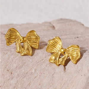 Boucles d'oreilles nœud dorées avec détail cœur sur une base en pierre naturelle