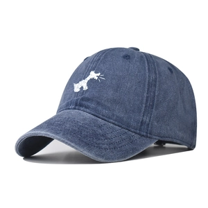 Close-up of a blue washed cotton baseball cap with white dog embroidery and curved brim