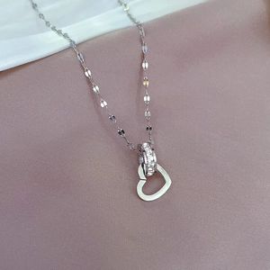 Macro detail of gold plated titanium necklace featuring crystal paved ring and heart pendant