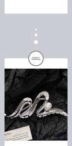 Silver S-shaped metal hair claw clip with pearl detail on black wrinkled paper