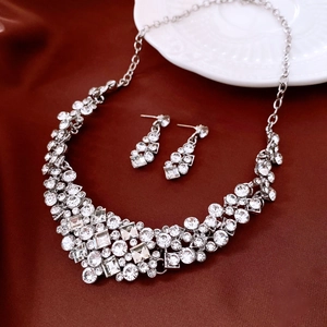 Close-up of diamond-encrusted rhombic pendant and earrings set on elegant silk fabric