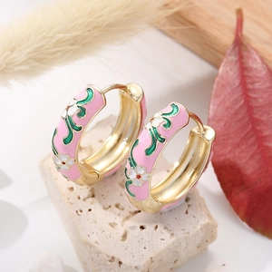 Detailed view of enamel floral hoop earrings with white flowers on pink background