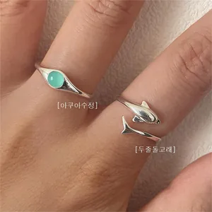 Detailed shot of 925 silver rings featuring aqua crystal and dolphin open band design