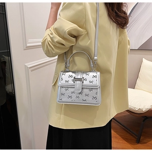 Mini borsa quadrata argento con fiocchi neri indossata da una modella in ambiente moderno