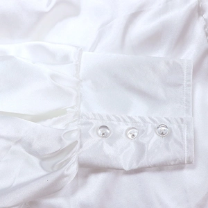 Détail macro de poignets en satin blanc élégants avec boutons en strass brillants