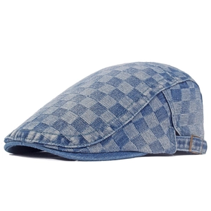 Close-up of denim newsboy cap featuring a blue checkerboard pattern and metal buckle