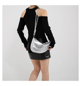 Detail of silver half-moon crossbody bag with knot design and textured metallic finish
