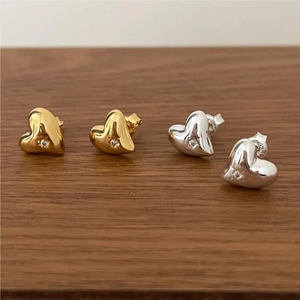 Detailed view of heart-shaped 925 silver stud earrings with zircon on dark wood surface