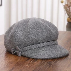 Detail shot of a grey wool newsboy hat featuring a delicate bow with bead accents