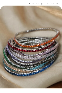 Macro view of stacked colorful zircon tennis bracelets on premium champagne satin fabric