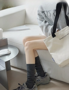Detail of dark charcoal ribbed knee-high socks in a cozy minimalist cotton style