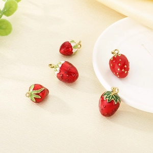 Detailed view of red enamel strawberry charms with gold hooks and green leaves